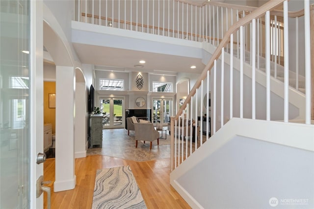 entryway featuring a fireplace, recessed lighting, stairway, a towering ceiling, and wood finished floors