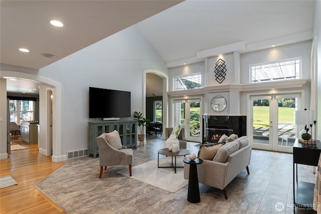 living area with a glass covered fireplace, a healthy amount of sunlight, visible vents, and arched walkways