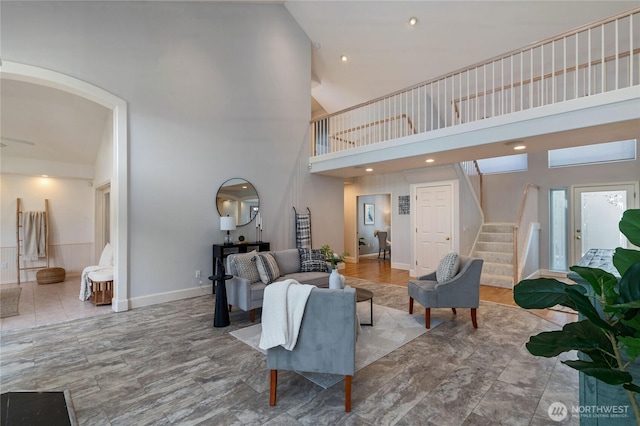 living room featuring baseboards, a high ceiling, and stairway