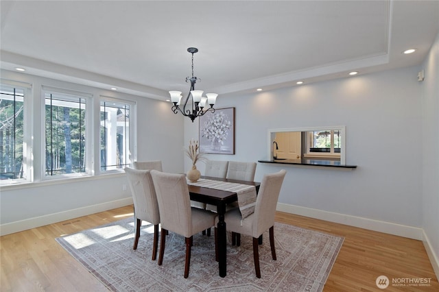 dining room featuring light wood finished floors, baseboards, a raised ceiling, and recessed lighting