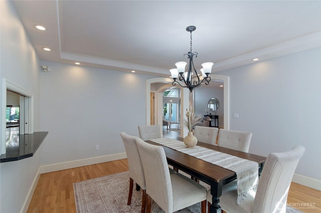 dining room featuring arched walkways, a notable chandelier, recessed lighting, light wood-style flooring, and baseboards