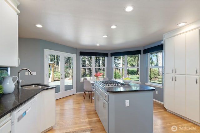 kitchen featuring white dishwasher, french doors, light wood-style floors, white cabinetry, and a sink