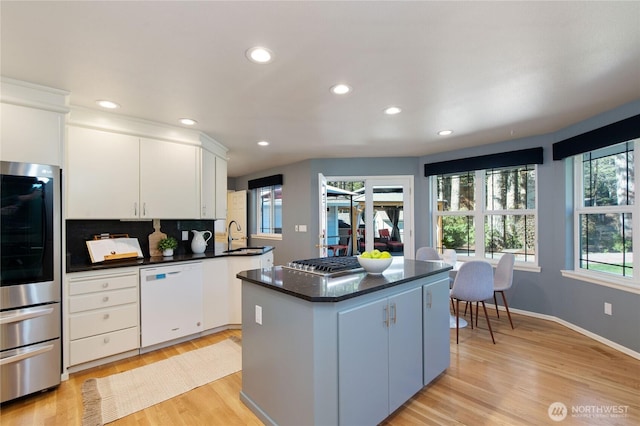 kitchen with dark countertops, a kitchen island, appliances with stainless steel finishes, and a sink