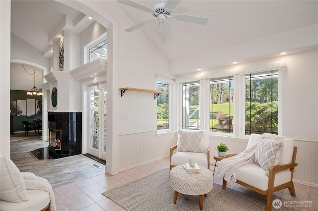 sunroom / solarium featuring visible vents, arched walkways, a high end fireplace, lofted ceiling, and ceiling fan with notable chandelier