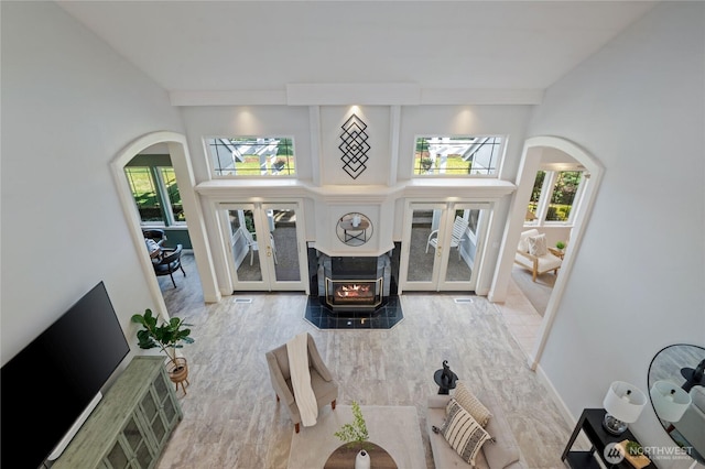 living room with arched walkways, french doors, plenty of natural light, and wood finished floors