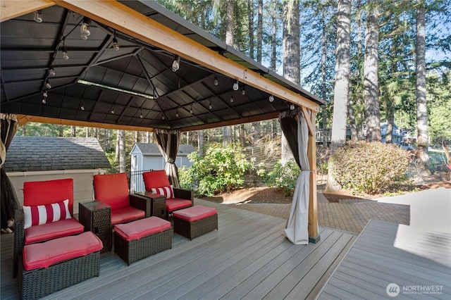 wooden deck with outdoor lounge area, an outdoor structure, a gazebo, and a storage unit