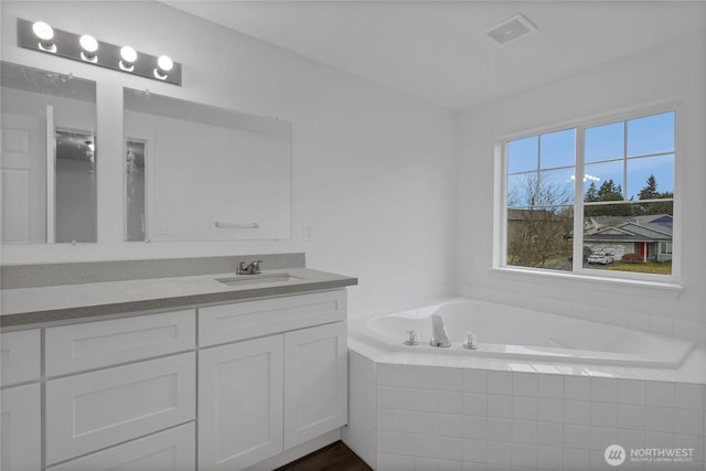 full bathroom with a bath, vanity, and visible vents