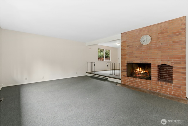 unfurnished living room featuring a brick fireplace, carpet, baseboards, and beam ceiling