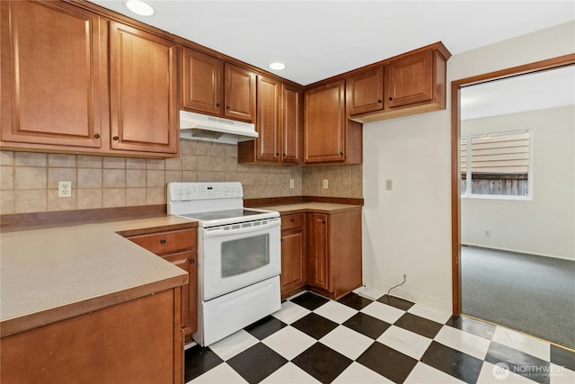 kitchen with tasteful backsplash, brown cabinetry, dark floors, white electric range, and under cabinet range hood