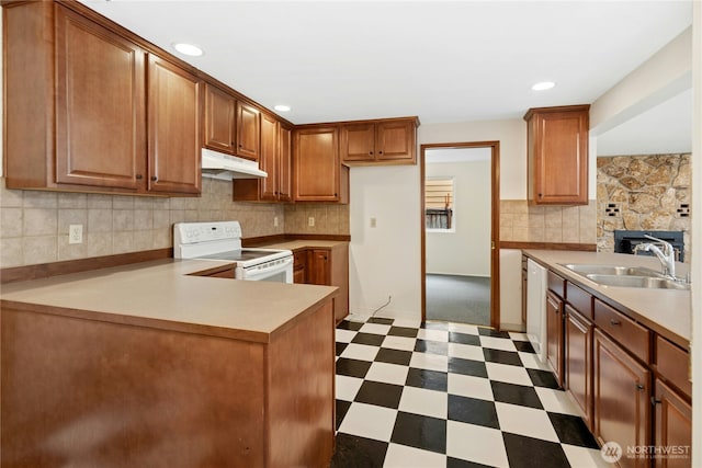 kitchen featuring white appliances, tile patterned floors, a peninsula, under cabinet range hood, and a sink