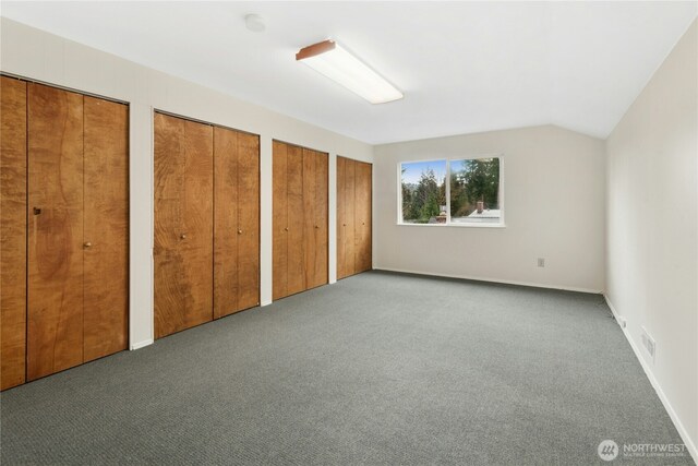 unfurnished bedroom featuring carpet flooring, visible vents, baseboards, vaulted ceiling, and multiple closets