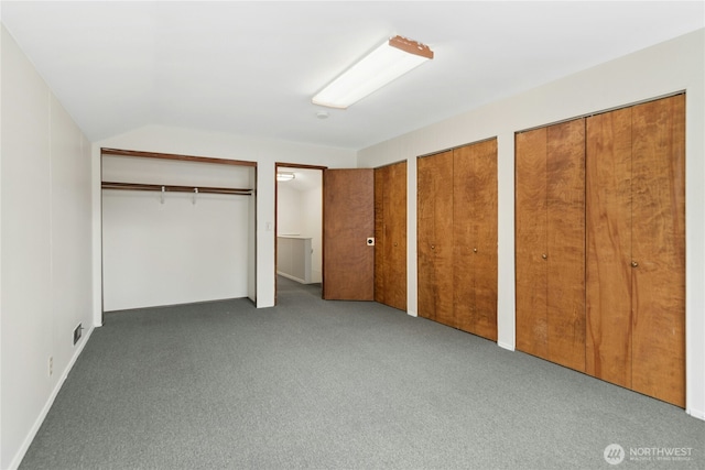 unfurnished bedroom featuring lofted ceiling, carpet, and two closets