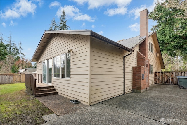 view of home's exterior with a patio, fence, a yard, a gate, and a chimney