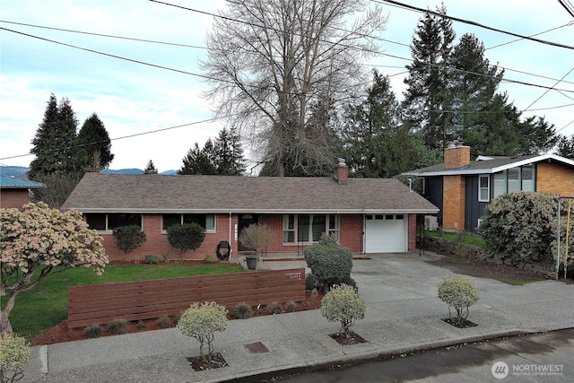 view of front of home featuring a front lawn, driveway, a garage, brick siding, and a chimney