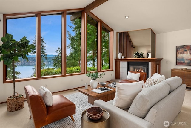 living area featuring lofted ceiling, a tiled fireplace, and baseboards