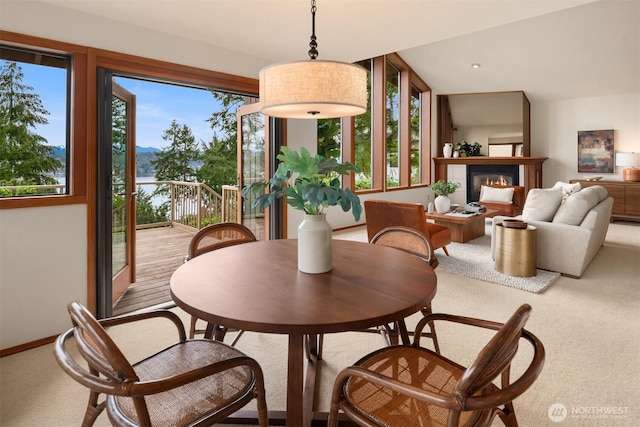 carpeted dining space featuring a glass covered fireplace and a wealth of natural light