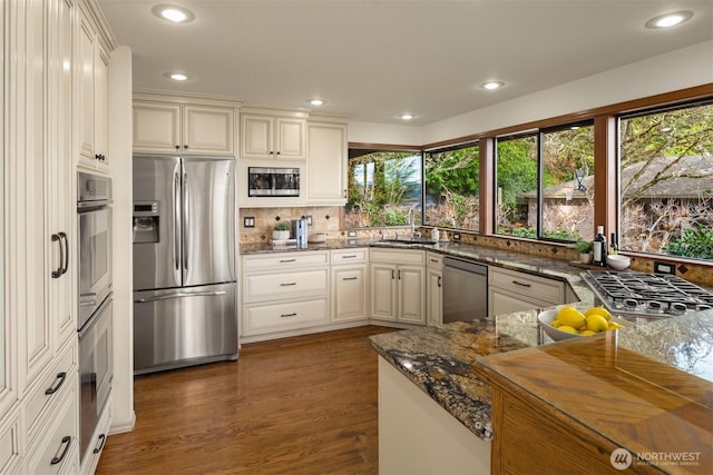 kitchen with recessed lighting, stainless steel appliances, tasteful backsplash, dark stone countertops, and dark wood finished floors