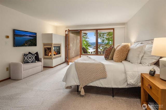 bedroom featuring baseboards, carpet flooring, access to exterior, and a multi sided fireplace