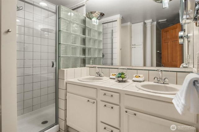 bathroom featuring a stall shower, a sink, backsplash, and double vanity