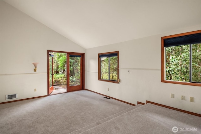 carpeted spare room featuring high vaulted ceiling, visible vents, and baseboards