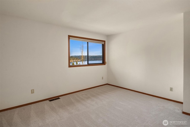 empty room featuring carpet, visible vents, and baseboards