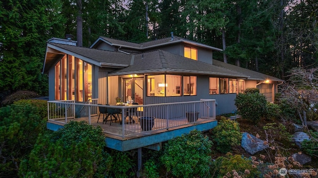 back of property with a deck and roof with shingles