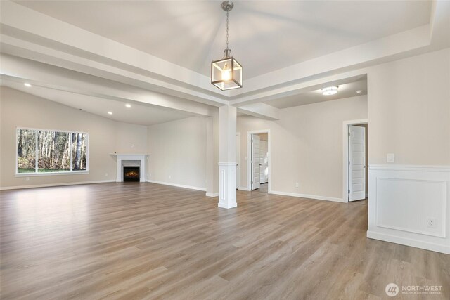 10707 212th St E, Graham, WA 98338 - unfurnished living room with lofted ceiling, light wood-style floors, a raised ceiling, and a premium fireplace