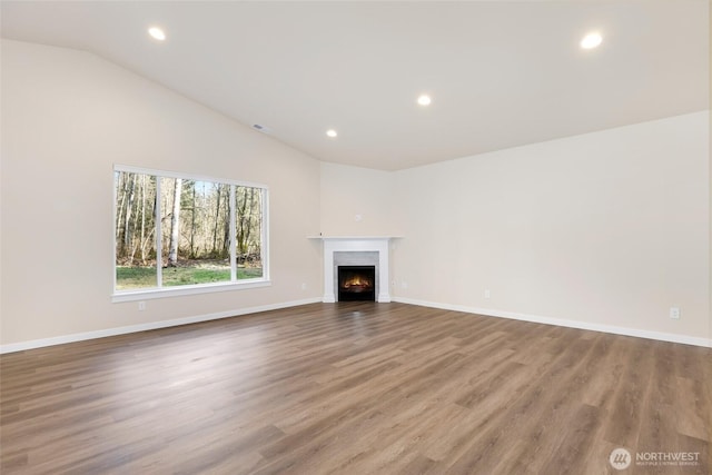 10707 212th St E, Graham, WA 98338 - unfurnished living room featuring recessed lighting, lofted ceiling, a warm lit fireplace, and wood finished floors