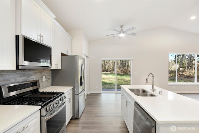 10707 212th St E, Graham, WA 98338 - kitchen featuring a sink, stainless steel appliances, light countertops, decorative backsplash, and vaulted ceiling