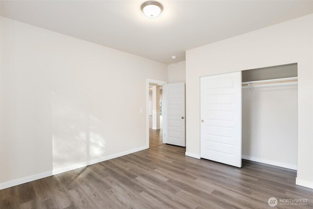 10707 212th St E, Graham, WA 98338 - unfurnished bedroom with wood finished floors, baseboards, and a closet