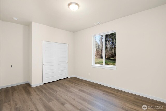 10707 212th St E, Graham, WA 98338 - unfurnished bedroom with a closet, baseboards, visible vents, and wood finished floors
