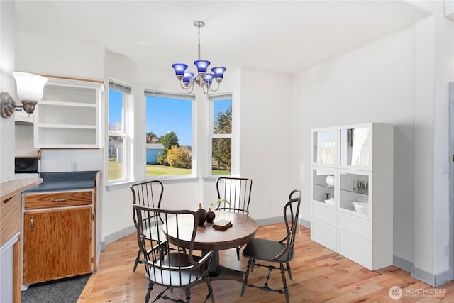 dining area featuring light wood-style flooring, baseboards, and an inviting chandelier