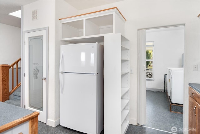 kitchen featuring visible vents, open shelves, washer / clothes dryer, and freestanding refrigerator