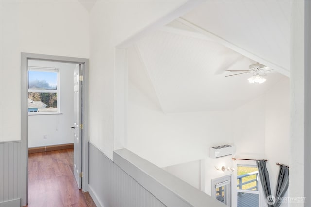 hallway featuring lofted ceiling, a wainscoted wall, and wood finished floors