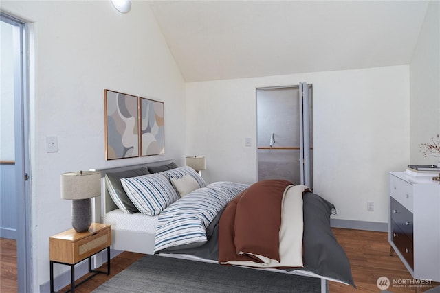 bedroom with vaulted ceiling, wood finished floors, and baseboards