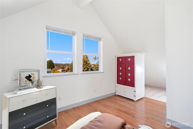 unfurnished room featuring vaulted ceiling with beams, light wood-type flooring, and baseboards