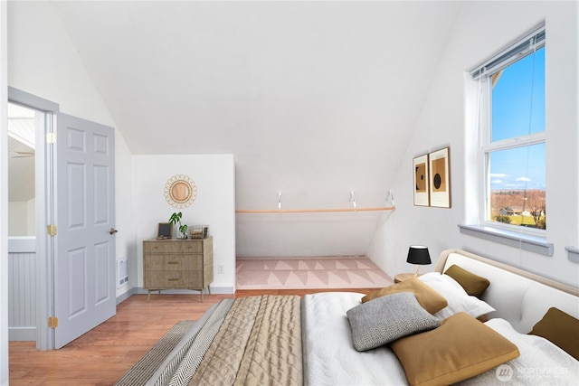 bedroom with lofted ceiling, visible vents, and wood finished floors