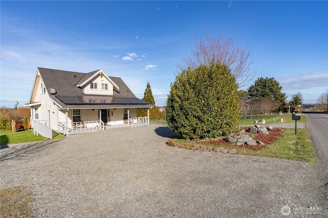 view of front of property featuring covered porch and gravel driveway