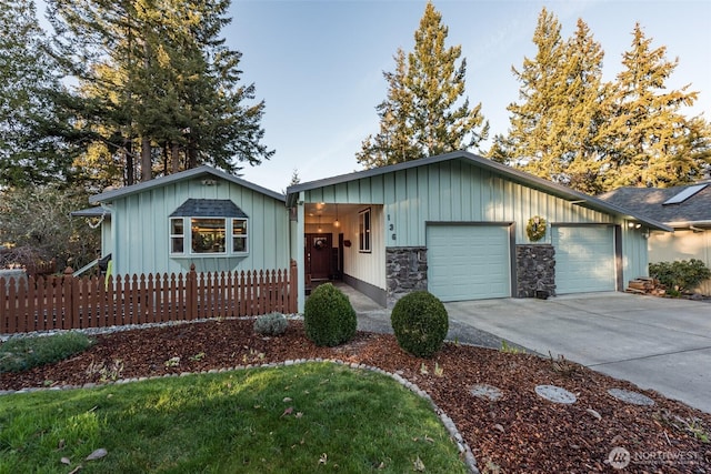 single story home with board and batten siding, fence, a garage, stone siding, and driveway