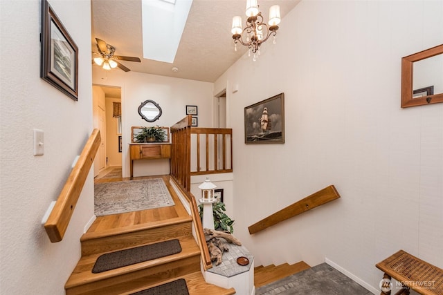 stairway featuring ceiling fan and a skylight