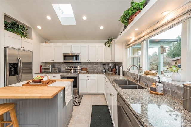 kitchen featuring appliances with stainless steel finishes, white cabinetry, a sink, and wood counters