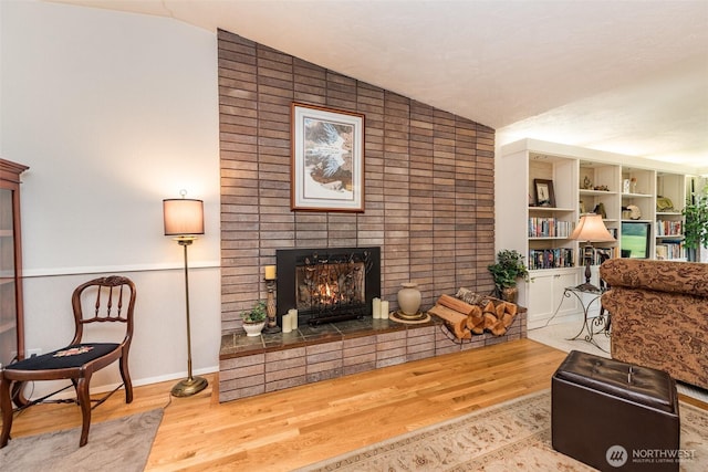 living room featuring lofted ceiling, a fireplace, and wood finished floors