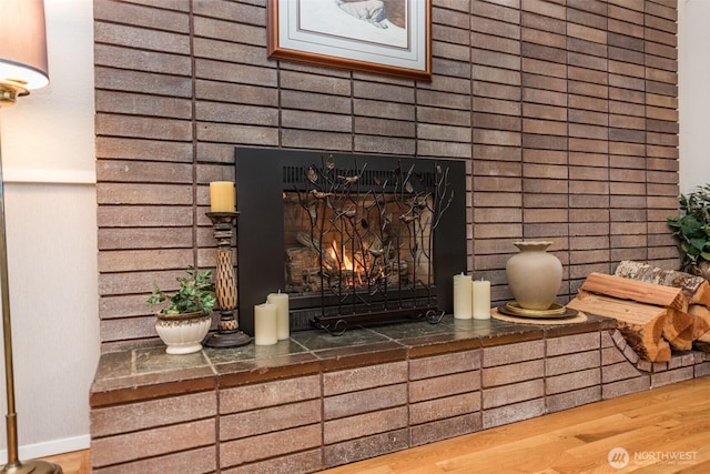 room details featuring a brick fireplace, baseboards, and wood finished floors