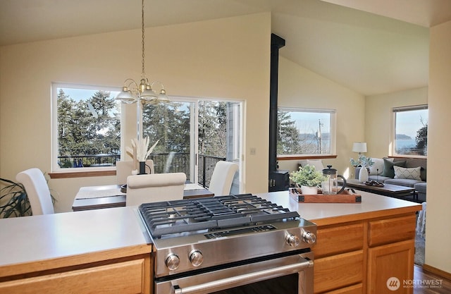 kitchen with decorative light fixtures, lofted ceiling, light countertops, an inviting chandelier, and gas stove