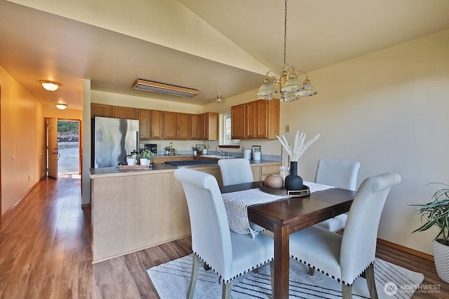 dining area featuring lofted ceiling, an inviting chandelier, and wood finished floors