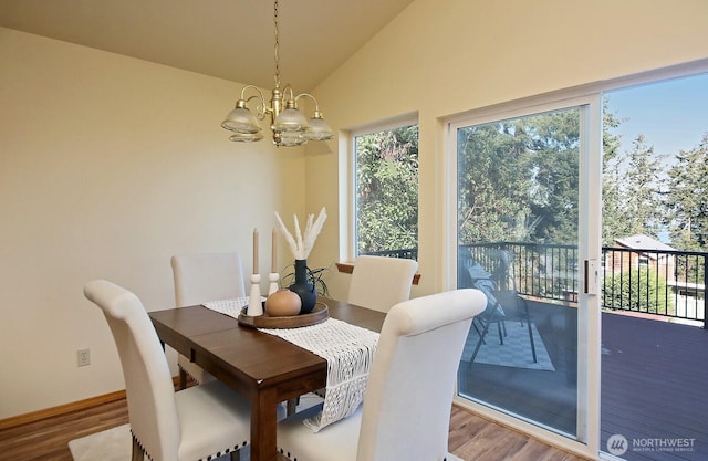 dining area with a chandelier, lofted ceiling, and wood finished floors