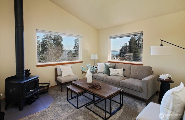 carpeted living area featuring a wood stove and vaulted ceiling