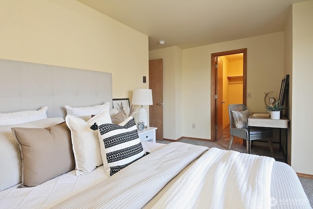 carpeted bedroom featuring a walk in closet, a closet, and baseboards