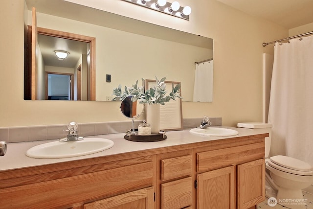 full bath with toilet, a shower with curtain, double vanity, and a sink