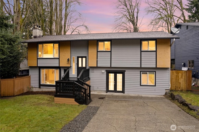 bi-level home featuring french doors, a front lawn, a chimney, and fence